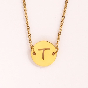 Détail d'un collier en acier inoxydable doré avec un pendentif pièce creux lettre T