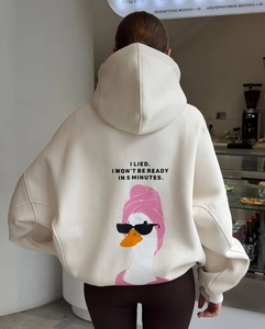 Detail of cartoon duck print and slogan on back of oversized cream hooded sweatshirt