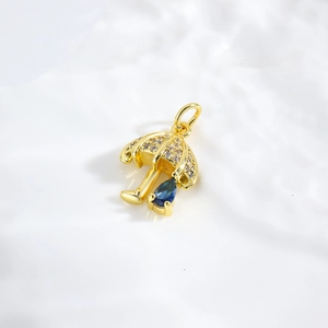 Dettaglio del ciondolo a ombrello dorato con zircone blu a goccia e micro-intarsio