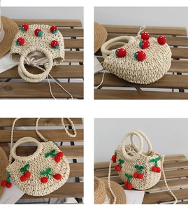 Detailansicht der Strohtasche mit handgefertigten Häkel-Erdbeeren und Kirschdekor