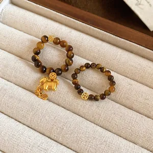 Tiger eye stone bead stretch rings with gold horse charm and coin bead in jewelry tray