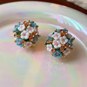 Makroaufnahme von Blumenohrringen mit hellblauen und rosa Blütenblättern und Bernsteinkristall