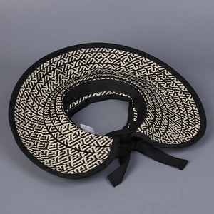 Detailed top view of a wide-brim sun visor featuring a chic black fabric bow tie