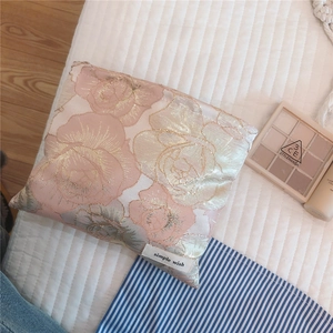 Detail of pink floral jacquard fabric with rose patterns on a small makeup bag