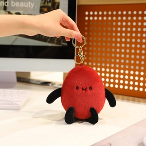 Close-up of a creative red plush peanut doll with a gold keychain on a modern desk