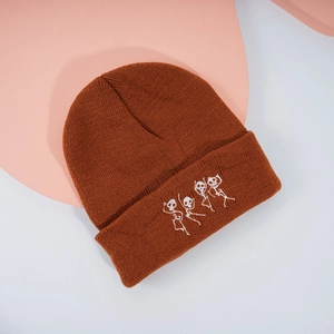 Gros plan sur le bonnet en tricot orange brûlé avec quatre motifs de squelettes dansants