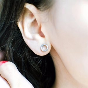 Close-up of minimalist silver hollow round geometric stud earrings on female model