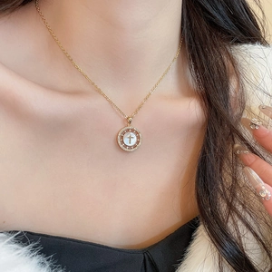 Gros plan du collier croix plaqué or 18 carats avec nacre et cristaux sur un mannequin