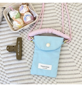 Detail of light blue fabric crossbody phone bag with thick pink padded shoulder strap