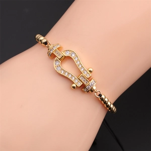 Close-up of gold horseshoe shackle bracelet with white zircon inlay on model's wrist