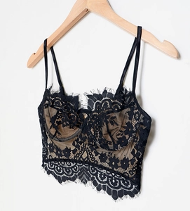 Detail of black eyelash lace bralette with nude lining hanging on a wooden hanger