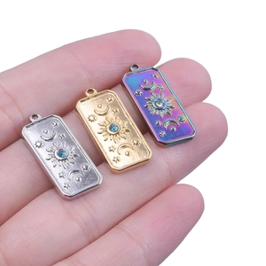 Detailansicht himmlischer rechteckiger Anhänger mit Sonnen- und Mondmotiven in Gold und Silber