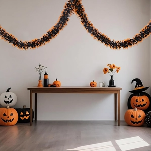 Detail view of orange and black pumpkin decorations with shiny Halloween tinsel garland