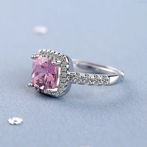 Luxurious silver ring with square pink gemstone and halo pavé diamonds from a side view