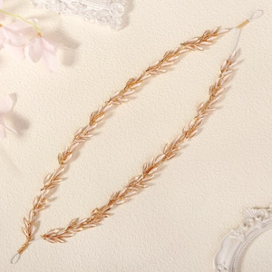 Detail of bridal headband featuring gold leaf motifs and creamy enamel petals on metal chain
