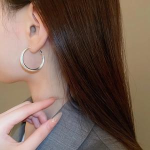 Close-up of wide silver-plated hoop earrings featuring a brushed metallic finish