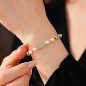 Bamboo style gold-plated bracelet featuring white pearls and green jade on a wrist