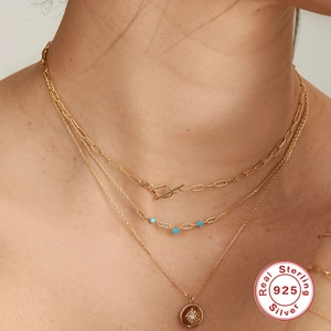 Detailed macro of triple-layer 925 silver gold chain with turquoise and sunburst charm