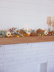 Detail of autumn garland with white pumpkins, maple leaves and warm LED light string