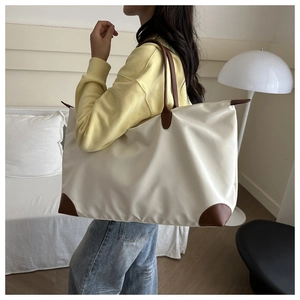 Detail of waterproof Oxford tote with brown leather straps shown on shoulder