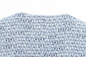 Detail of blue and white tweed vest neckline showing textured metallic woven fabric