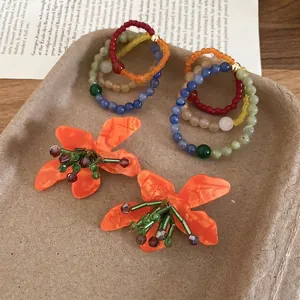 Bohemian floral earrings with matte petals and colorful beaded rings on eco tray