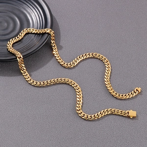Detailed close-up of a golden Cuban link chain necklace with a classic clasp on grey background