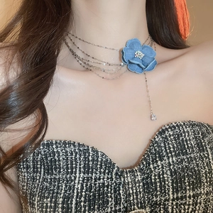 Gros plan du collier multicouche en métal avec fleur en denim et pendentif en zircone