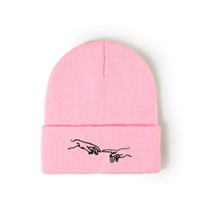 Détail du bonnet en maille rose avec broderie main noire et texture côtelée fine
