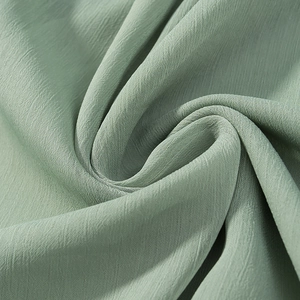 Detail of pea green pleated chiffon fabric showing lightweight breathable texture and drape