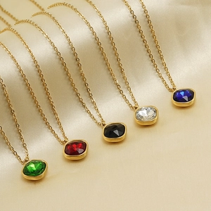Detail of square zircon pendants in five colors on golden chains over silk background