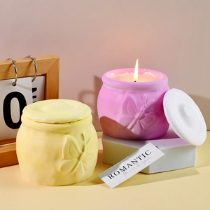 Detalle de tarros de velas amarillos y morados con relieve de mariposa en un soporte