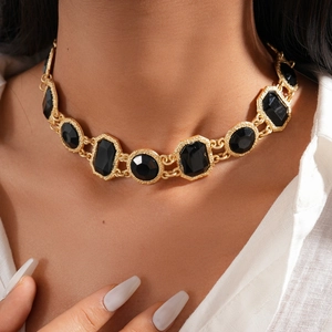 Gros plan du collier vintage doré avec pendentifs géométriques en cristal noir sur modèle