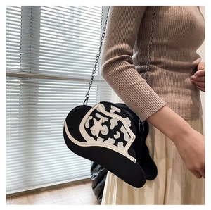 Detail view of a black cowboy hat shaped crossbody bag with star and cow print worn by model