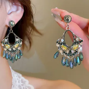 Close-up of vintage floral drop earrings with green zircon and teal teardrop beads