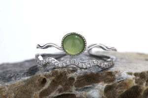 Macro shot of S925 silver ring with green gemstone on gray rock surface
