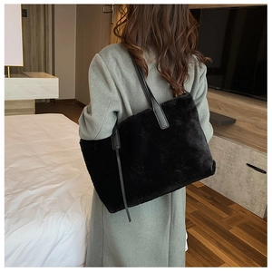 Vista laterale di una grande borsa tote nera in peluche indossata a spalla per l'inverno