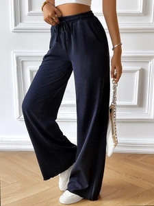 Close-up of deep blue pleated wide-leg pants featuring adjustable waist drawstring detail