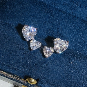 Sparkling silver stud earrings with double heart-shaped zircons on dark blue velvet