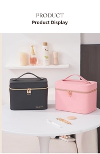 Detail of portable leather makeup cases in black and pink with metal zippers and handle
