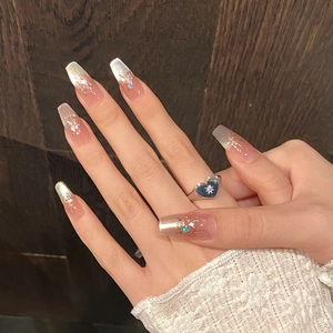 Nahaufnahme von Glitzer-Sargnägeln mit silbernem Herzring an der Hand des Models