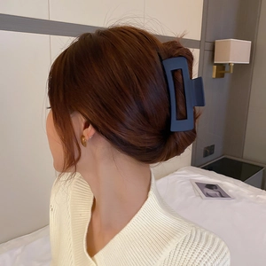 Pince à cheveux rectangulaire noir mat sur un chignon de femme avec un éclairage naturel
