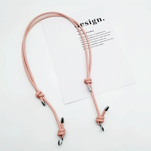 Detail of a slim pink adjustable PU leather shoulder strap with silver metal hooks