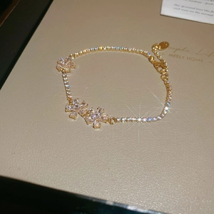 Detailed macro of gold flower bracelet with five marquise zirconia stones on adjustable chain
