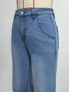 Détail de la texture du denim et du bouton métallique de ce jean bleu décontracté