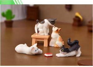 Detailed view of four realistic miniature resin cats with a wooden stool and tiny book