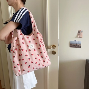 Détail du sac cabas en velours côtelé rose avec imprimé fraises porté par un mannequin