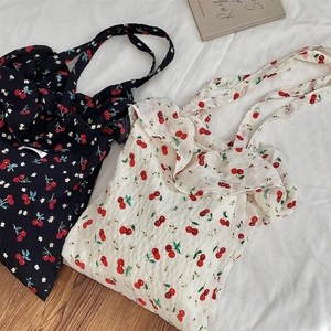 Detailed view of cherry print canvas tote bags with ruffled edges in navy and cream colors