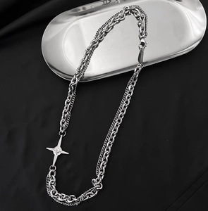 Detail einer silbernen doppellagigen Kette mit Sternanhänger auf einem Metalltablett