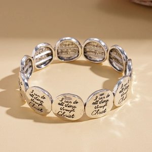 Vue détaillée des médaillons argentés gravés sur le bracelet élastique avec texte sacré